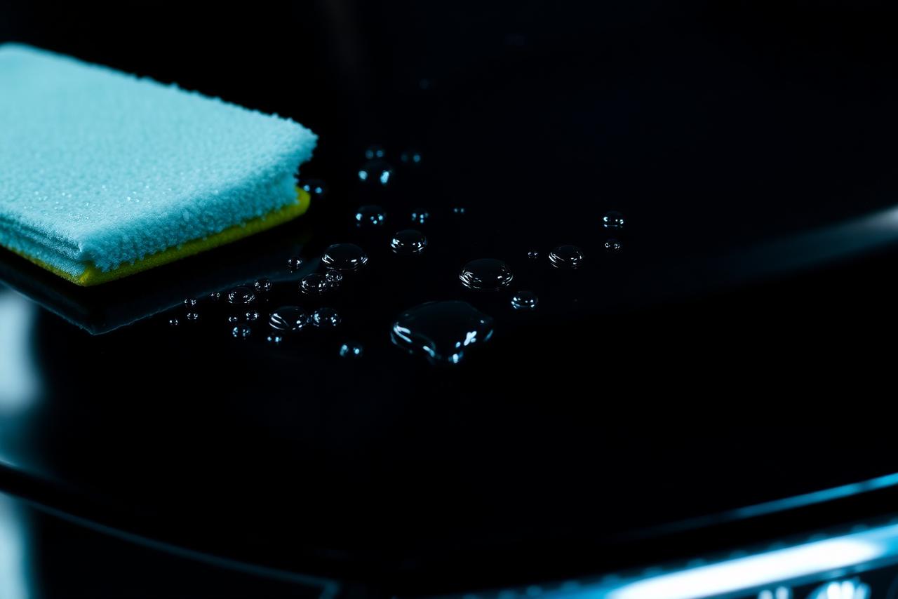 Water beading on ceramic coated car paint next to a wax pad — ceramic coating vs wax Qatar, Dosh Wash